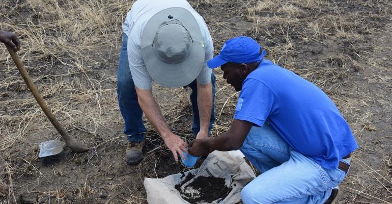 Two men take a soil sample