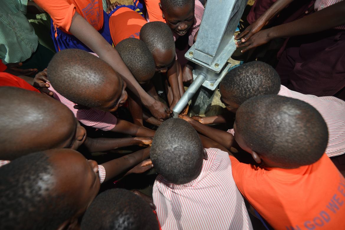 Afrikanische Kinder belagern eine Handpumpe