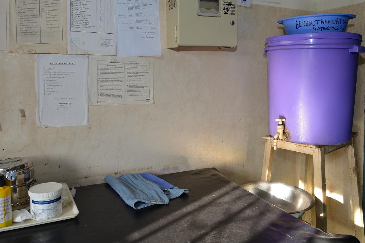 Salle de traitement. Un seau violet rempli d'eau se trouve dans un coin. C'est la réserve d'eau.