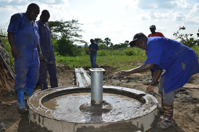 Workers build the foundation for a hand pump