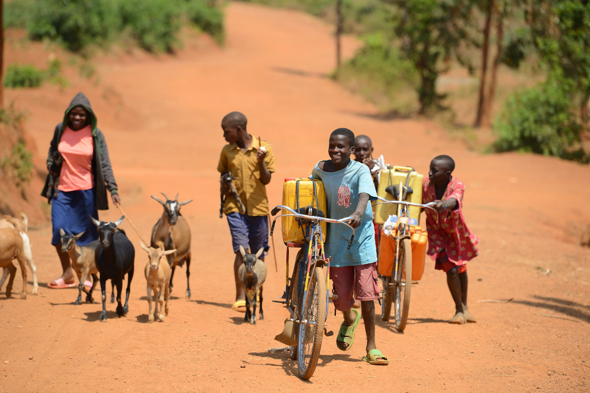 Des enfants avec des bicyclettes vont chercher de l'eau dans des bidons